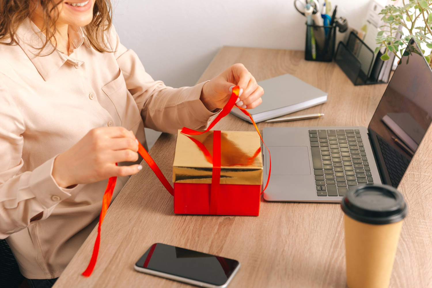 Photo sans visage d'une jeune femme déballant un cadeau rouge au bureau